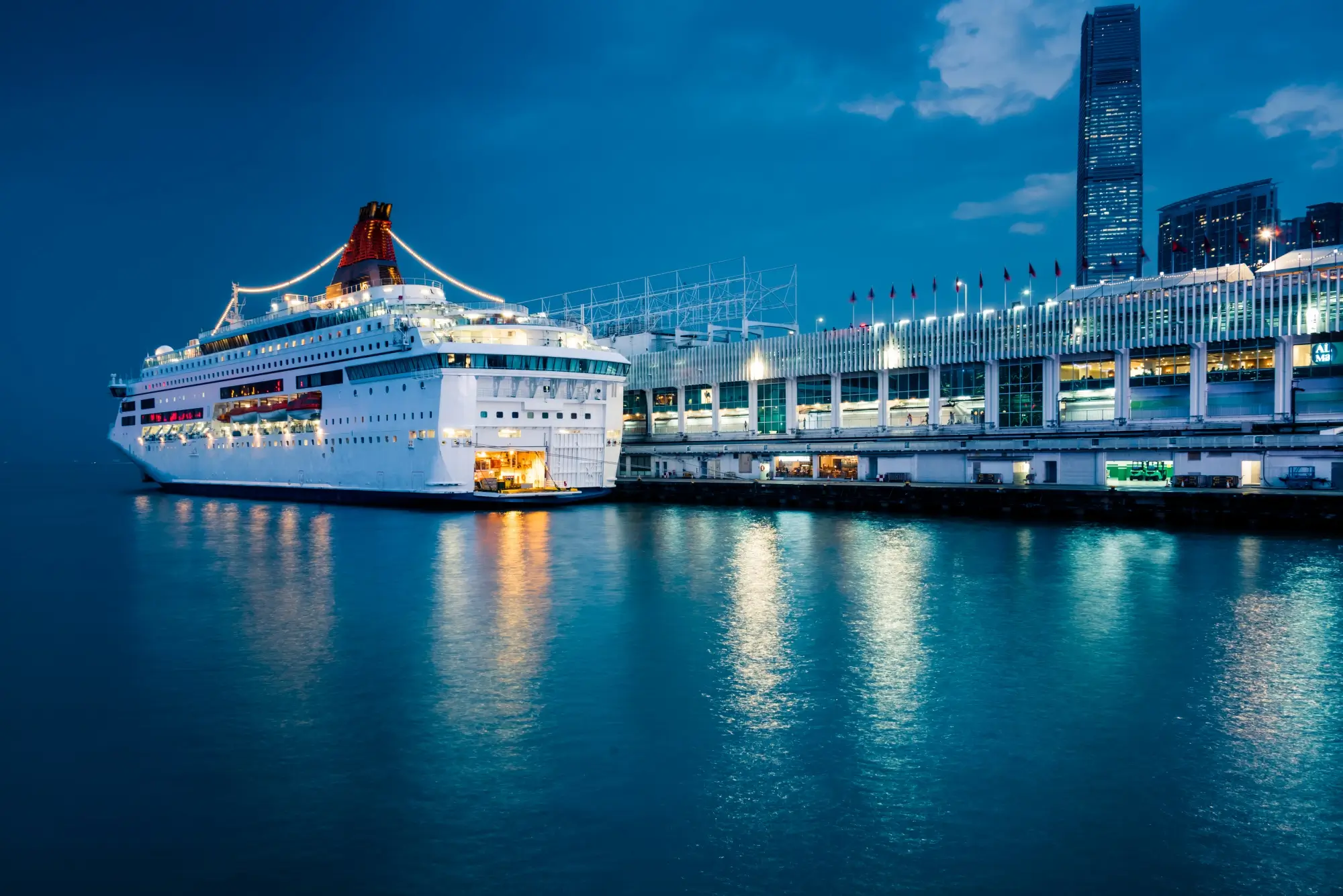Cruise ship docked at illuminated harbor terminal during blue hour