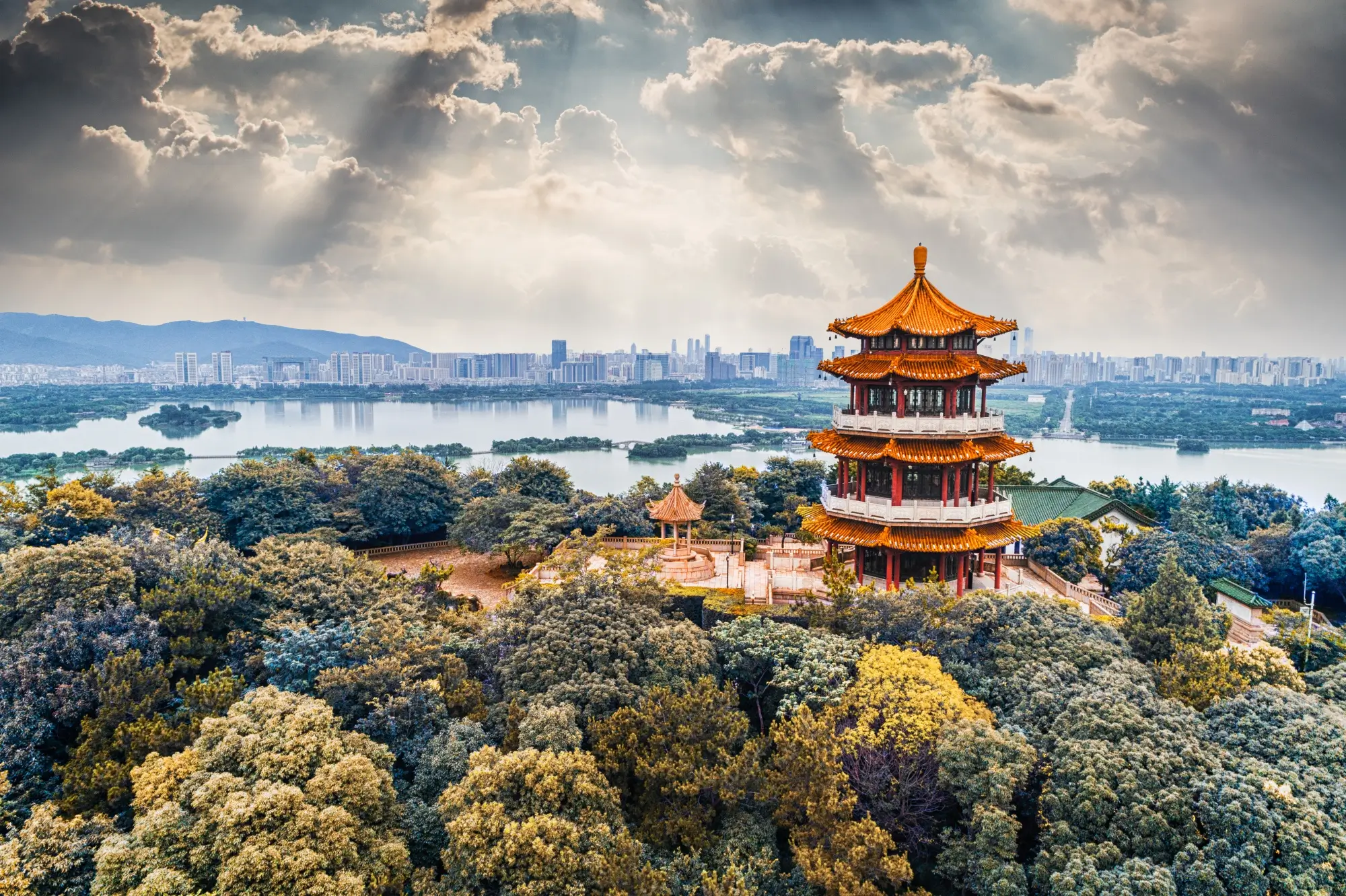 Traditional Chinese pagoda overlooking lake and modern city skyline