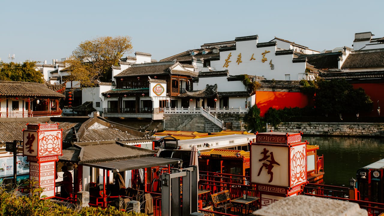 Traditional Chinese riverside architecture with boats and decorative lanterns