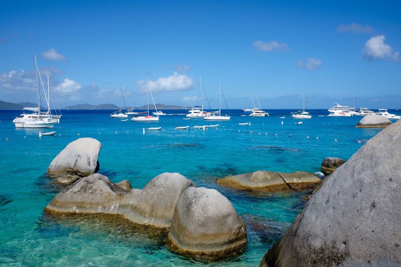 Caribbean seascape with sailboats, turquoise water and large coastal rocks