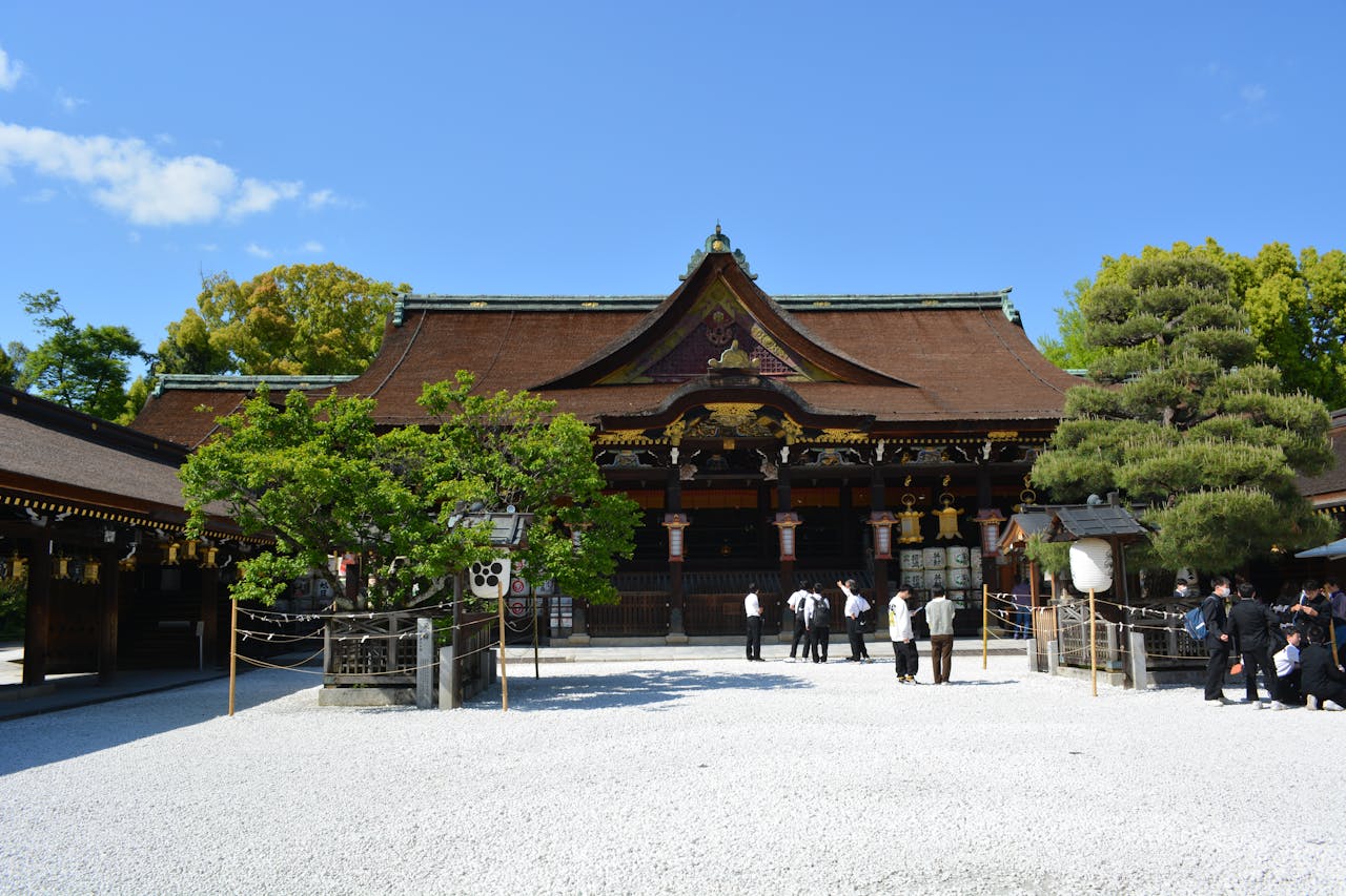 Traditional Japanese shrine surrounded by trees under clear blue sky