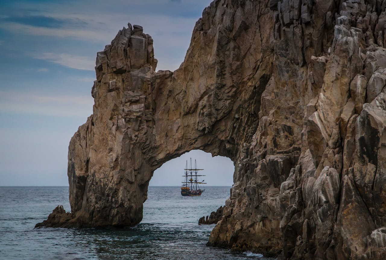 Natural rock arch at Cabo San Lucas with sailing ship beyond