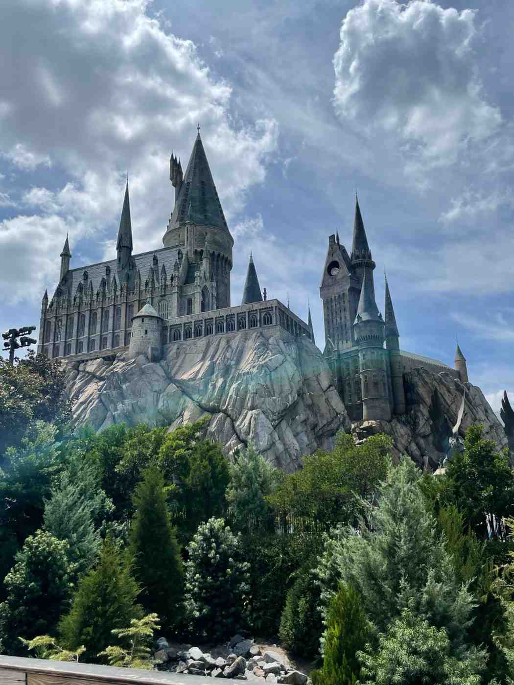 Hogwarts Castle attraction beneath dramatic clouds with lush landscaped surroundings