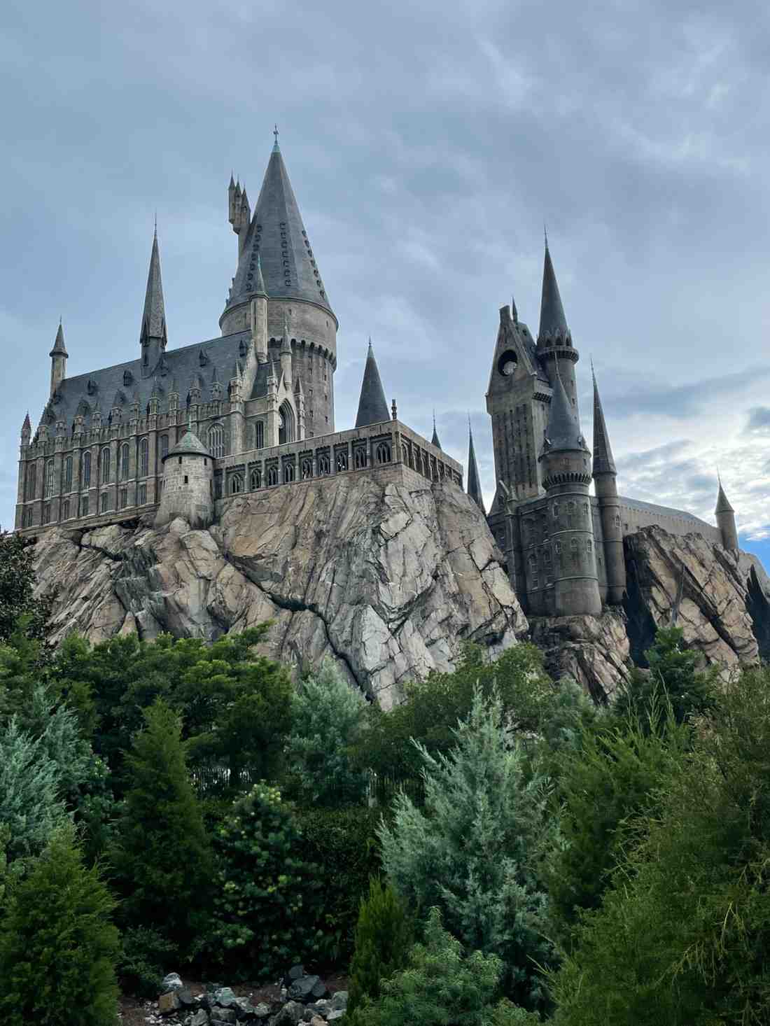 Hogwarts Castle attraction rising above rocky cliffs and surrounding greenery