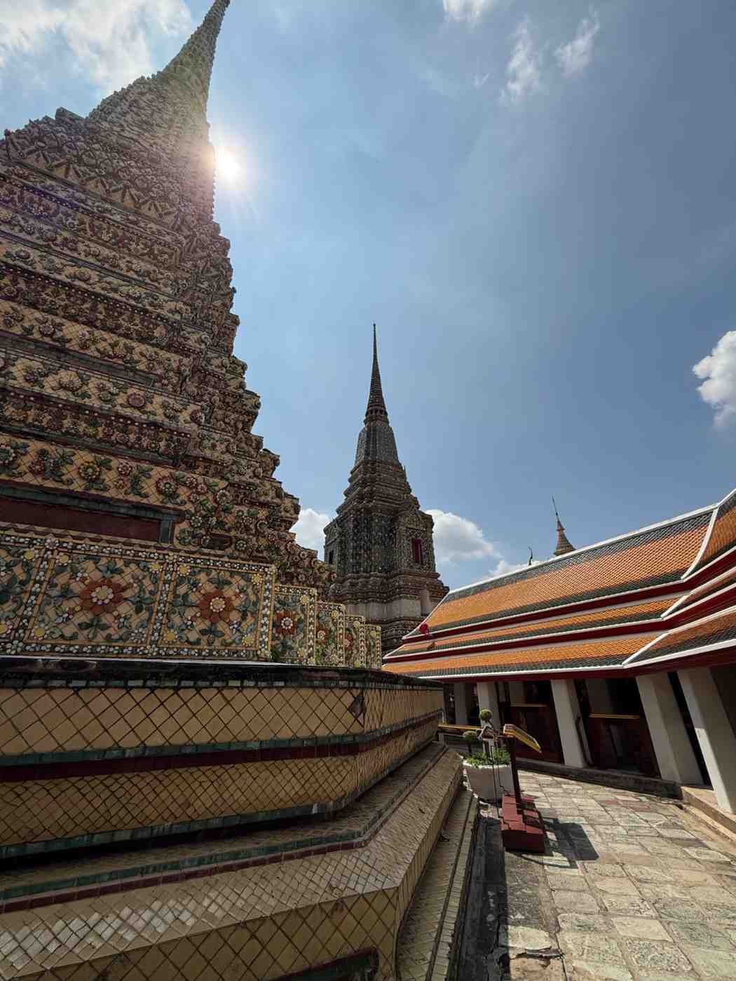 Decorated temple stupas and traditional architecture beneath a bright Bangkok sky