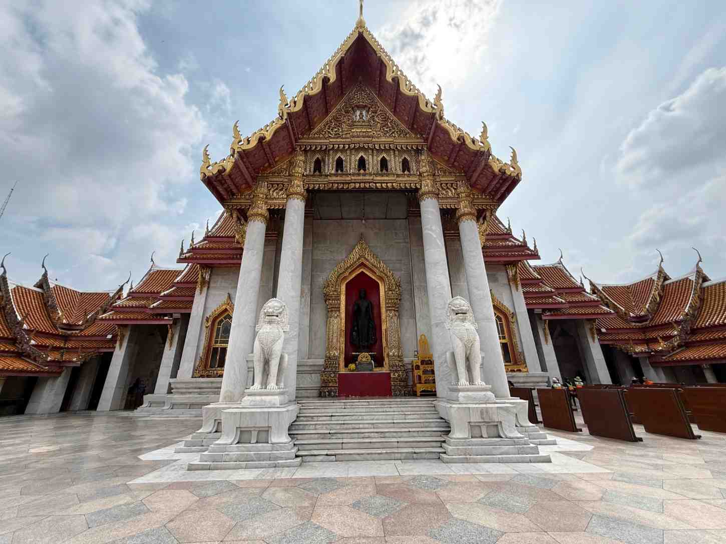 Ornate Thai Buddhist temple with golden details and traditional red roof